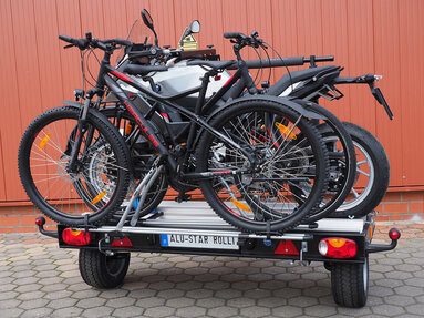 SMV Alu-Star Rolli frei stehend, Heckansicht. Maximale Beladung mit einem Motorrad auf der Plattform des Anhängers und zwei Fahrrädern auf dem optionalen Fahrradträger.